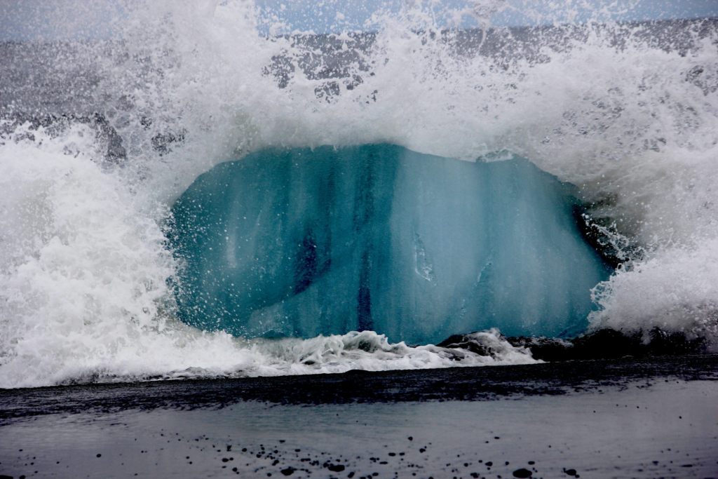 wave impacting ice on a sandy shore